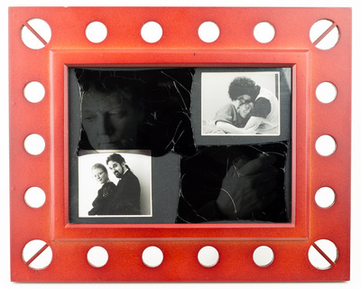 A reddish frame with a dark insert. The insert has two photographs of a couple, one in the upper right (the man and woman are cuddling) and the other in the lower left (the man and woman are posing). In the space between is a dark gray shadow of the woman, looking away from both couple pictures.