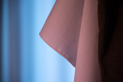 pinkish looking cloth on the left; bluish background; dark stripe on the right